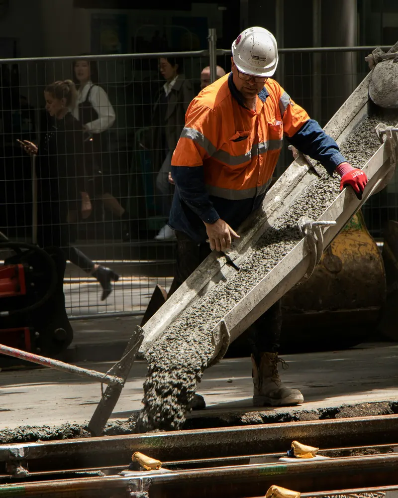 A worker guiding a concrete chute into wall forms.